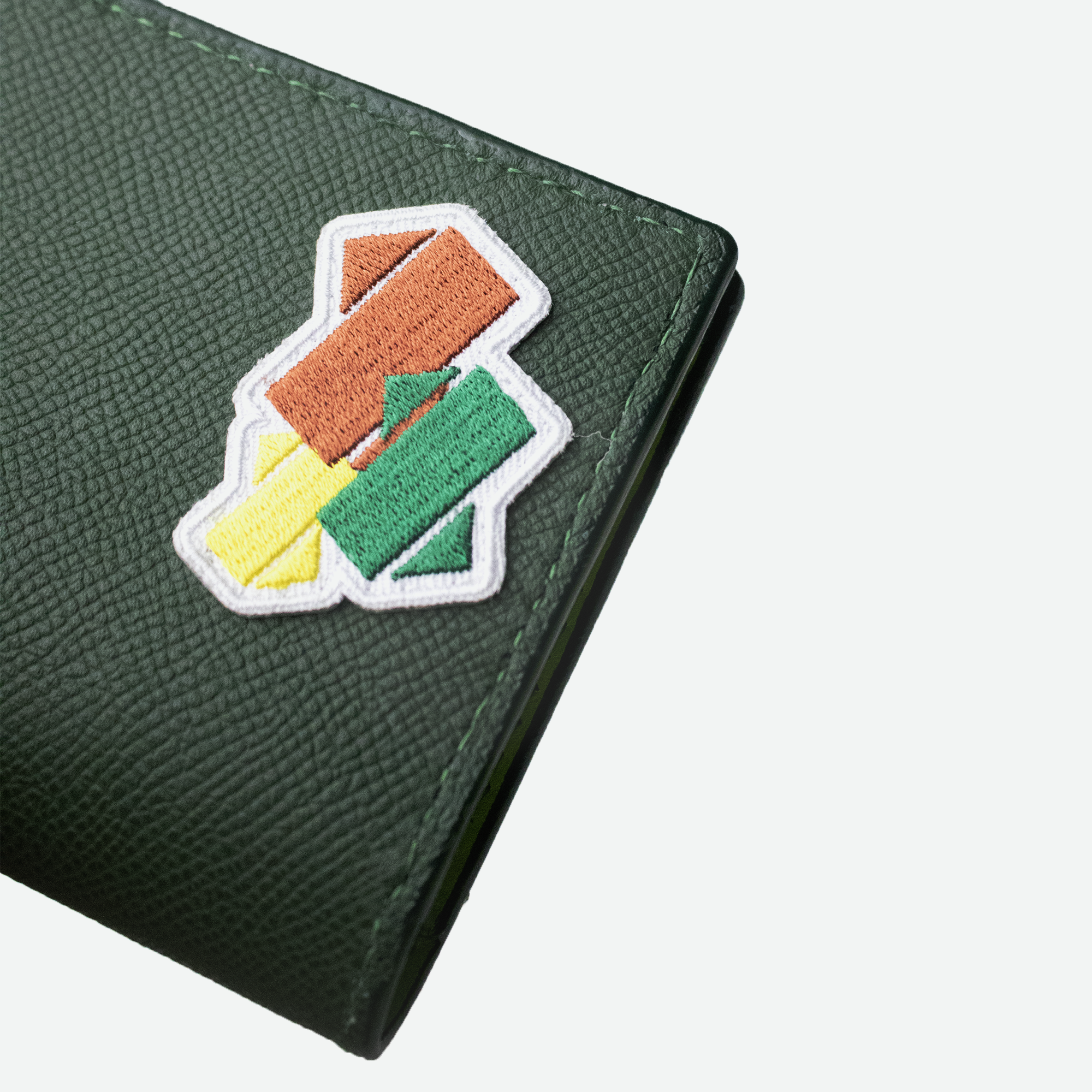 Nærbillede af det farverige broderede patch på det grynede grønne læder af Faubret’s pascover.