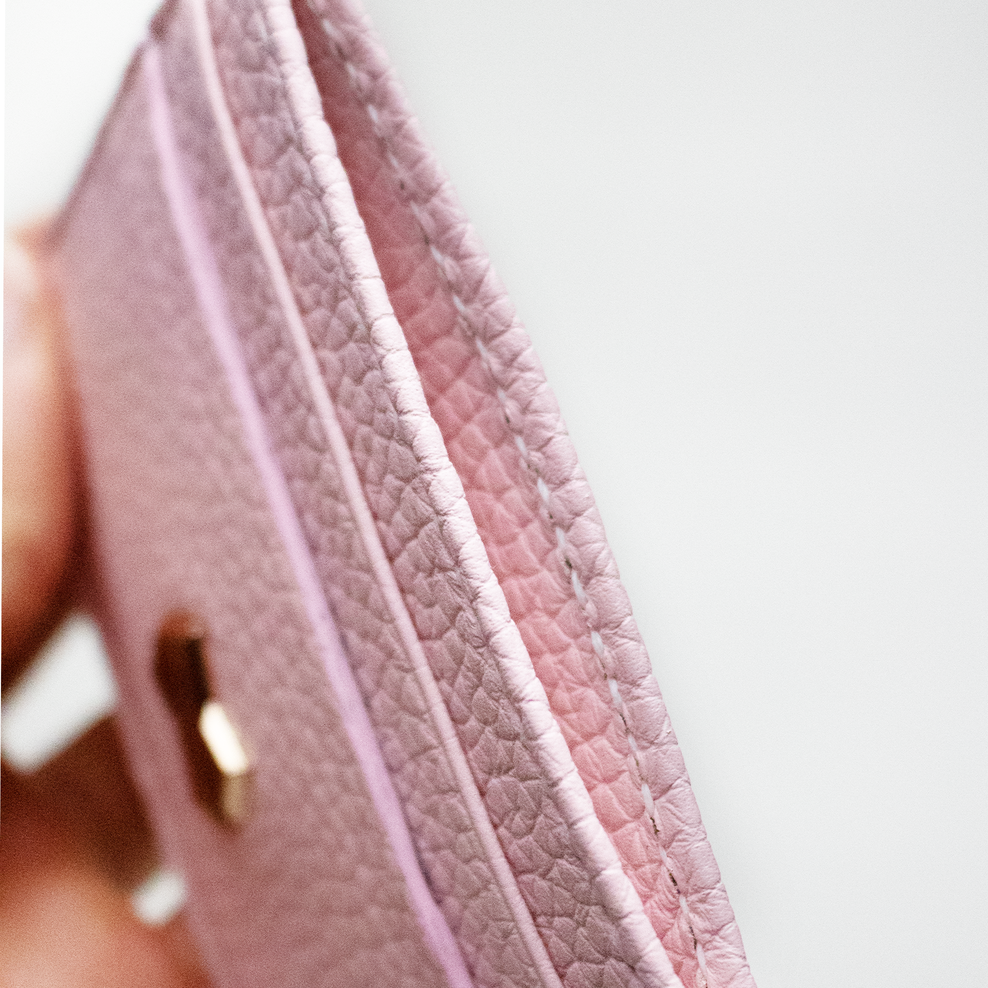 Nærbillede af sadelmager-syning og den prægede læderstruktur på den lyserøde Faubret kortholder.