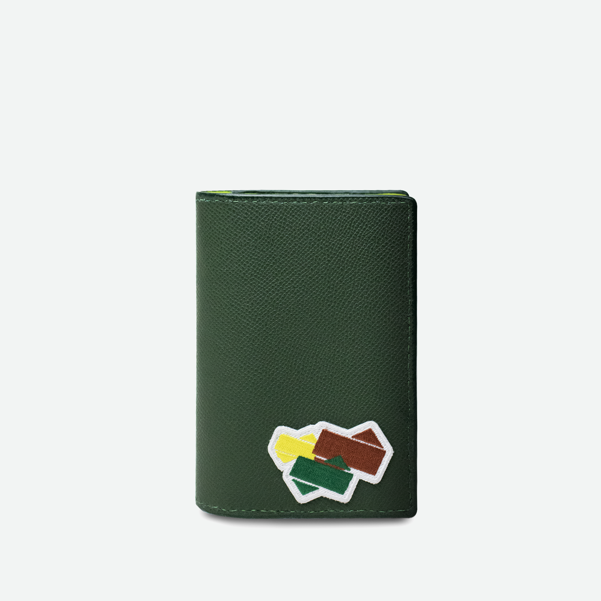 Forfra-visning af Faubret’s pascover i grynet grønt læder med farverigt broderet patch.