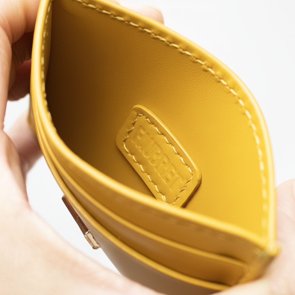 Indvendig detalje af gul læder kortholder med præget Faubret-logo, håndlavet med luksuriøse finish.