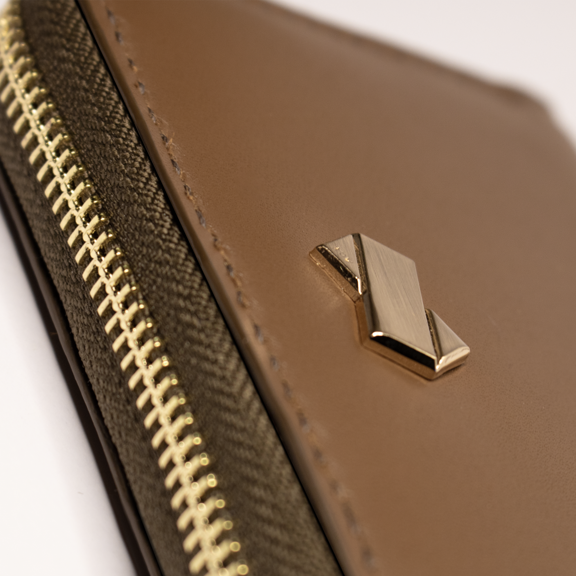 Nærbillede af det gyldne Faubret-logo på den brune Kortholder Pung Dame i læder.