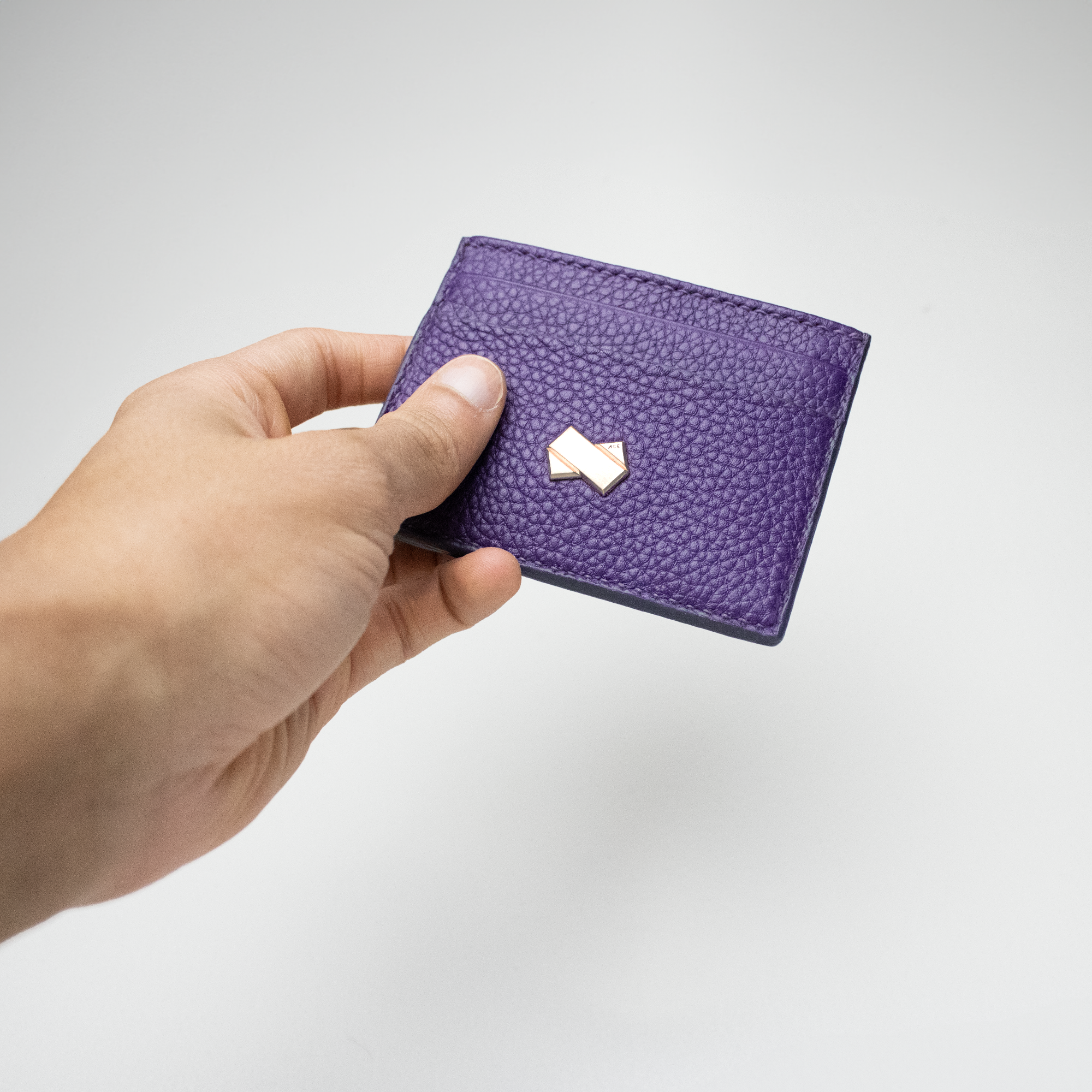 Den lilla Faubret kortholder i præget læder holdt i hånden, symbol på feminin luksus og moderne stil.