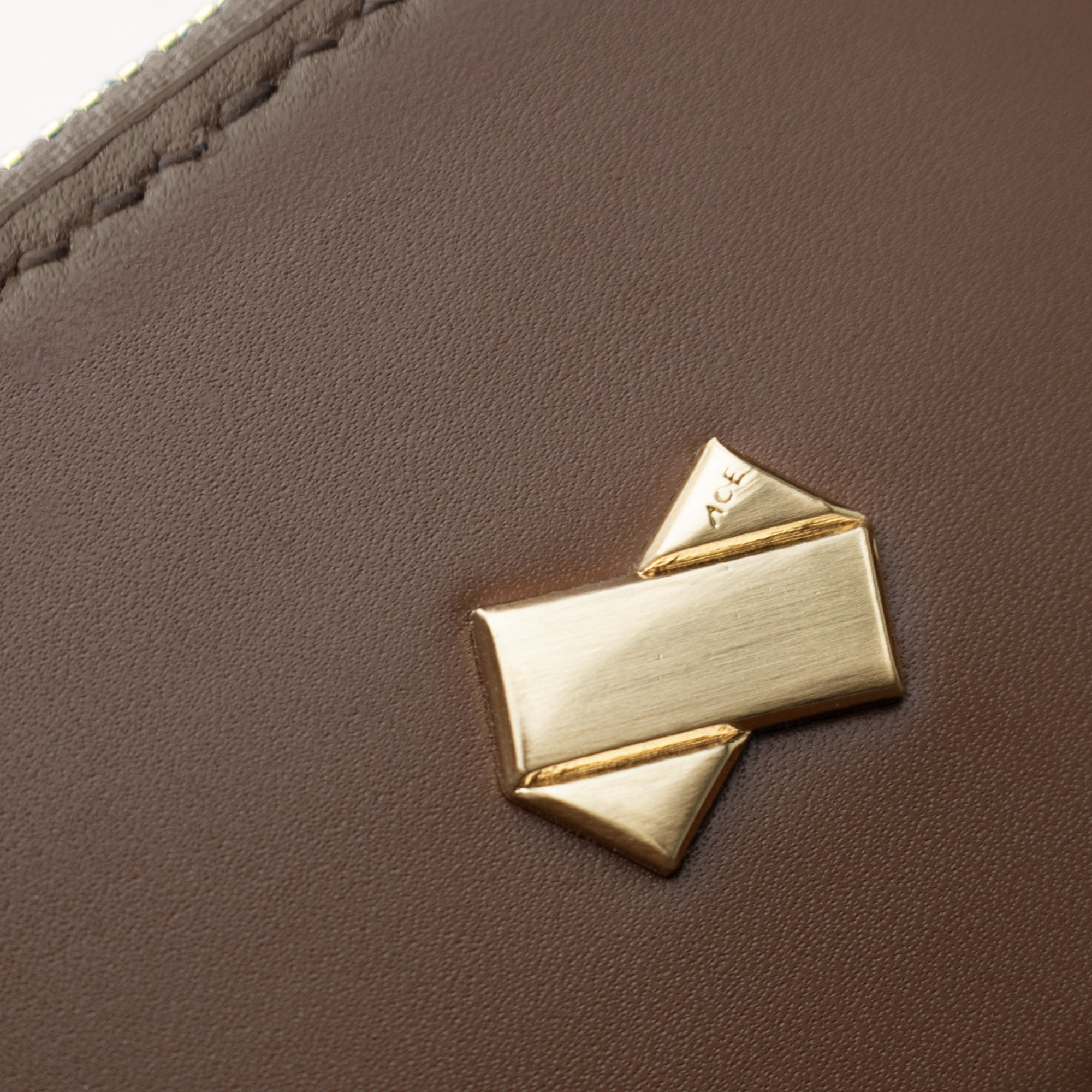 Detalje af Faubret guldlogo præget på glat brun koskindslæder.