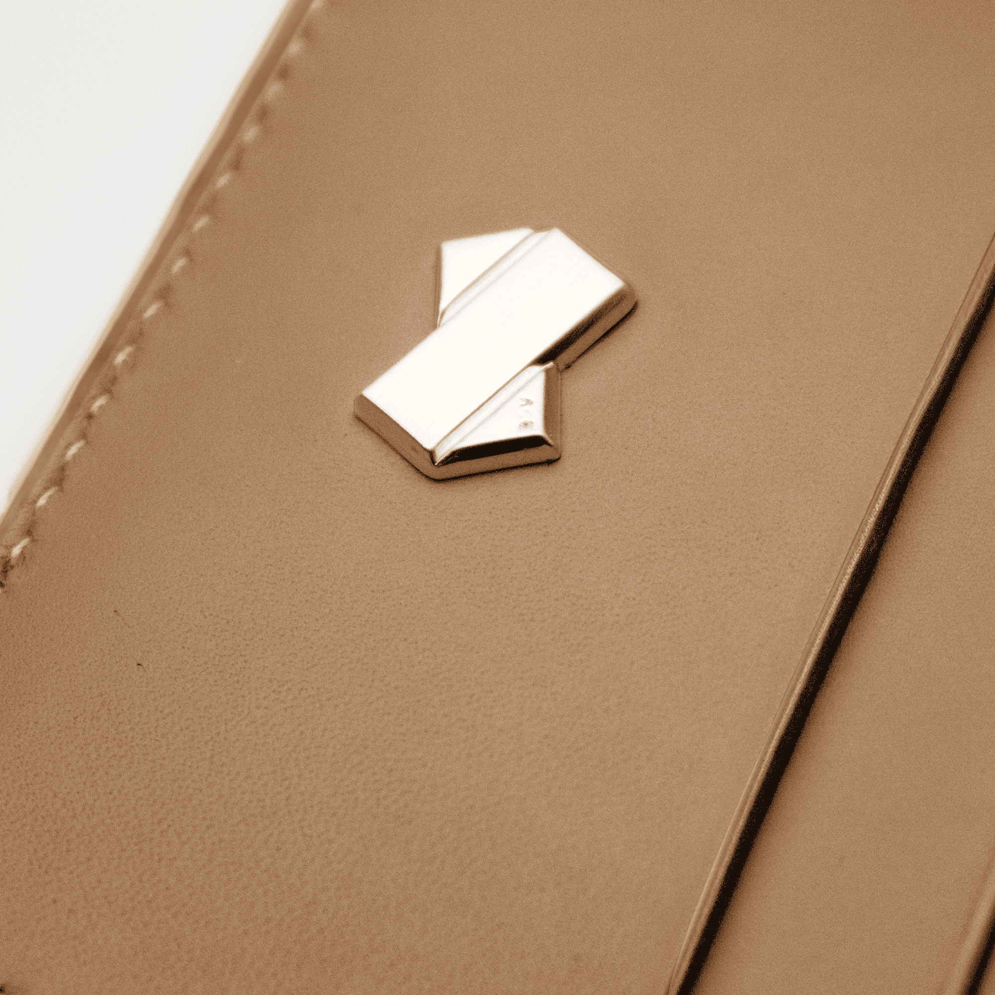 Detalje af kortholder i beige læder til kvinder, viser den glatte lædertekstur og det gyldne logo i relief.