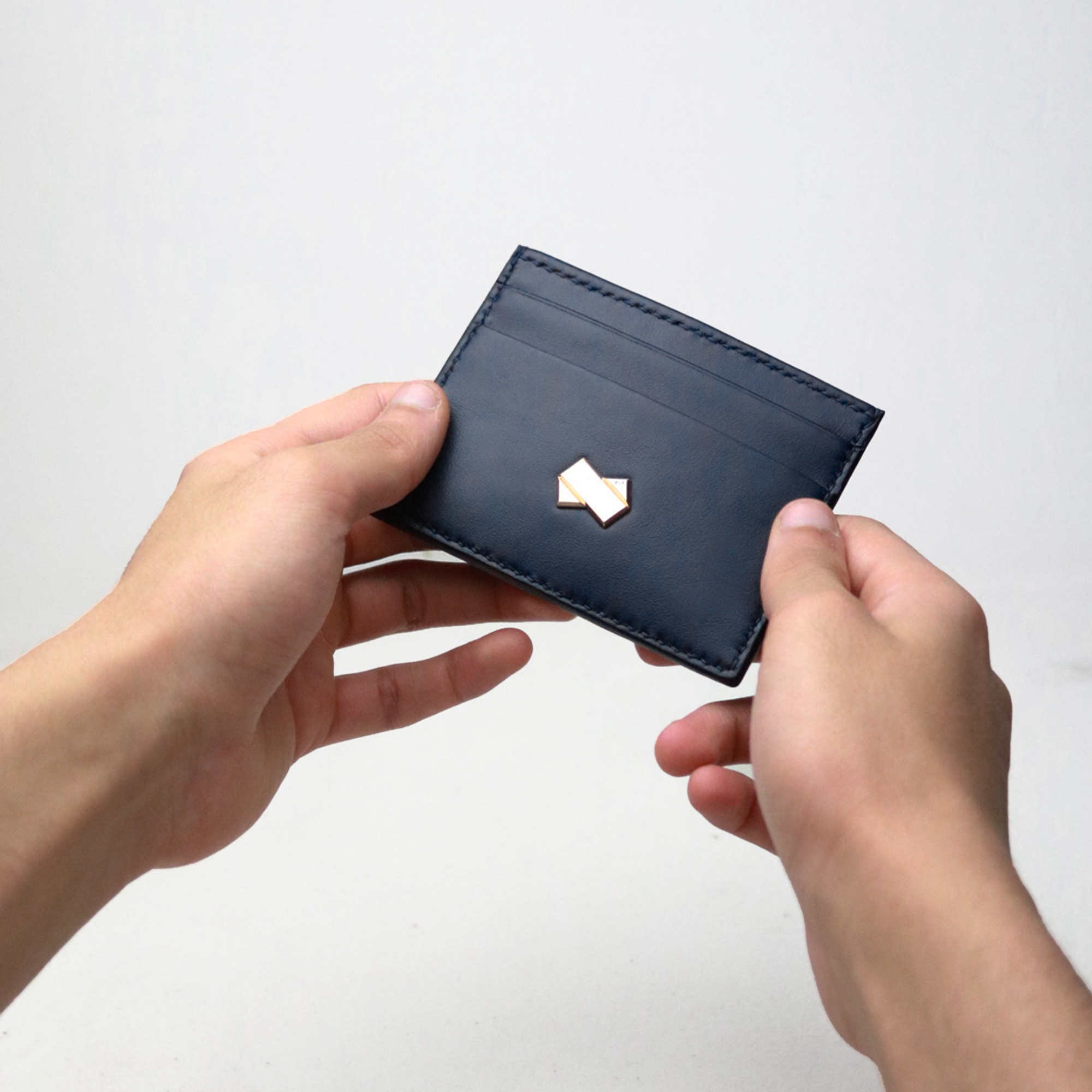 Faubret kortholder i navyblåt skind holdt i hånden, der fremhæver det kompakte og elegante design.